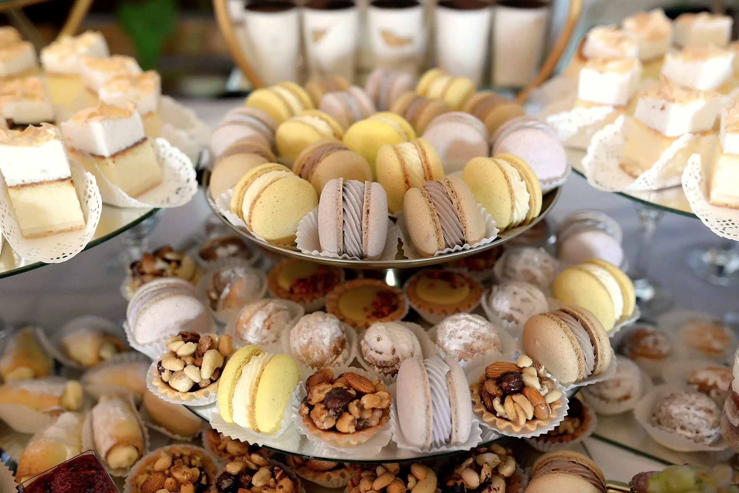 Ett fat i flera våningar med macarons, nötter och småkakor.